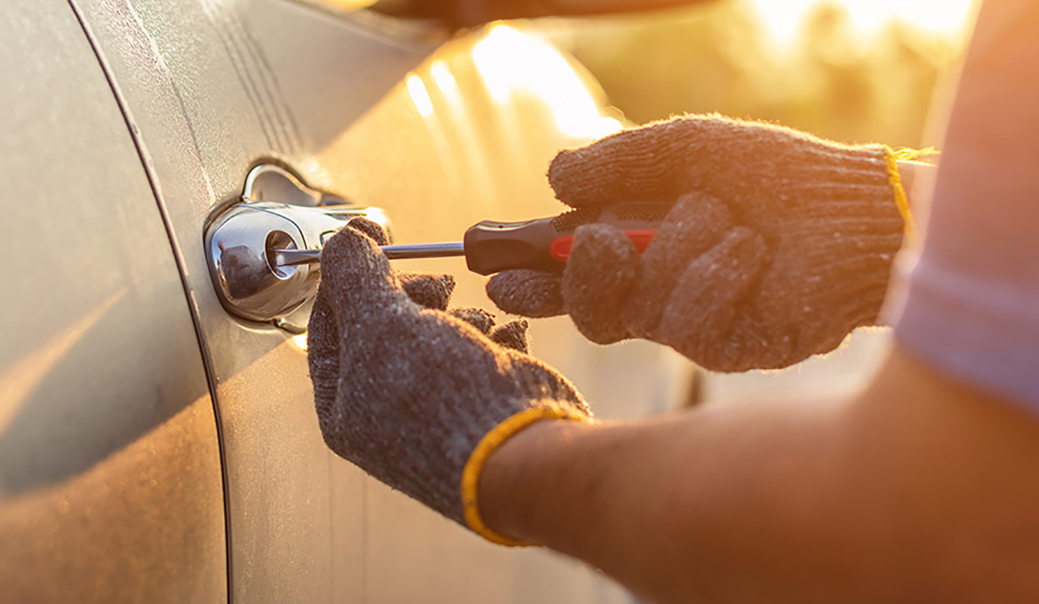 Car technician wearing white gloves and using screwdriver to fix, repair or open the door of modern car